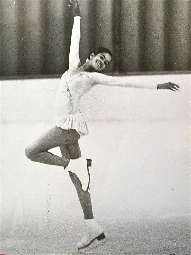 Black and white photo of Joan Camobell skating. She is a young African American woman wearing a white skating costume. 